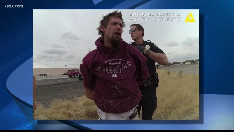 Police officer arresting man in red hoodie.