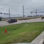 Cars and people at intersection under cloudy skies.