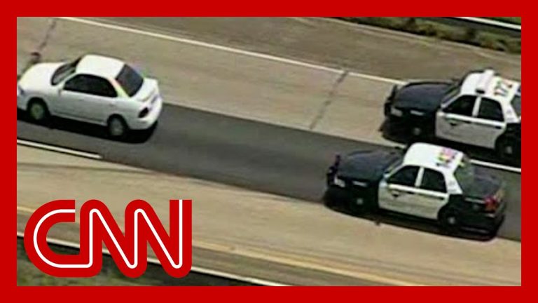Police chase white car on highway.