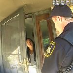 Police officer talking to woman at door