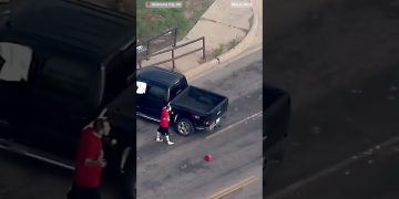 Man in red beside black pickup truck, Oklahoma City.