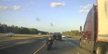Motorcycle and truck on a highway at sunset.