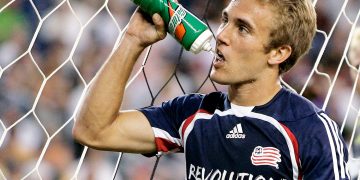 Soccer player drinks water during game break.
