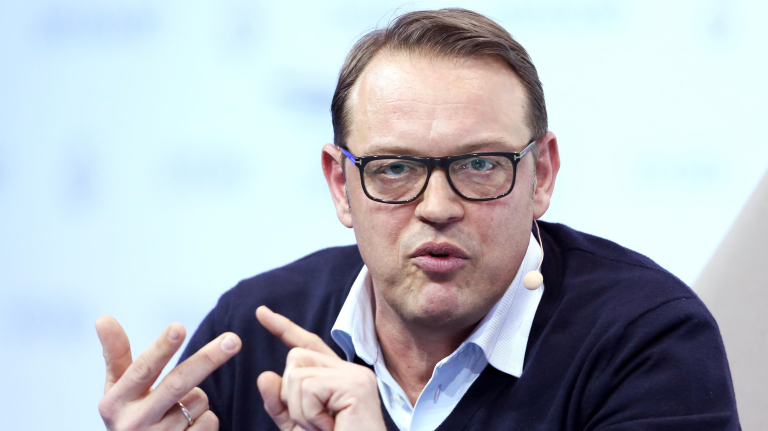 Person speaking with microphone and glasses.
