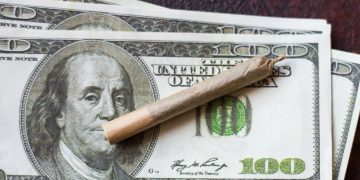 Rolled cigarette on hundred dollar bills
