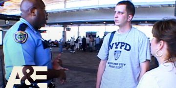 Police officer talking to travelers at airport.