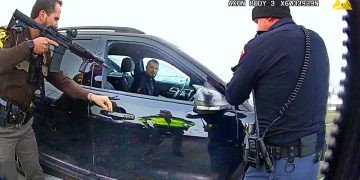 Police officers inspecting car during traffic stop.