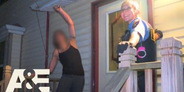 Police officer smiling on porch with man nearby.