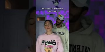 Couple standing indoors with humorous expressions.