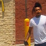 Person holding clipboard outside fast-food restaurant.