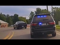 Police car pursuing black vehicle on road.