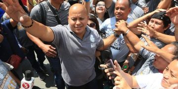 Man surrounded by crowd waving and cheering