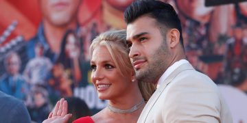 Couple smiling at movie premiere event.