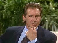 Person in suit with thoughtful expression, green background.