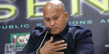 Man speaking at a press conference with microphone.
