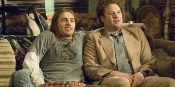 Two men sitting on a sofa, casual and relaxed.
