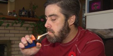 Man lighting a cigarette indoors.