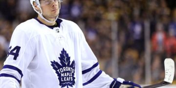 Hockey player in Toronto Maple Leafs jersey, holding stick.