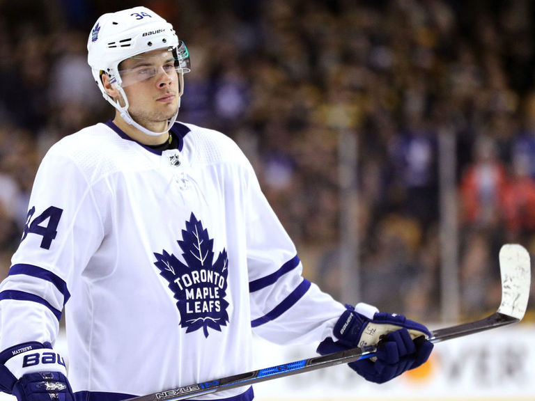 Hockey player in Toronto Maple Leafs jersey, holding stick.