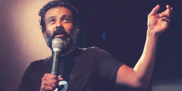 Man speaking passionately into a microphone on stage.
