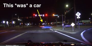 Nighttime road intersection with highlighted car movement.