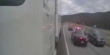 Police escorting trucks on highway.