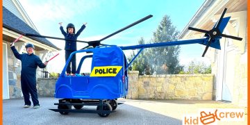Kids in toy police helicopter costume with props.