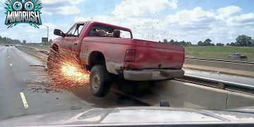 Red truck sparking against highway barrier