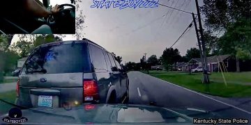 Police car dashcam footage of vehicle on suburban road.