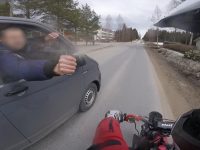 Biker giving fist bump to car passenger on road.
