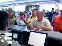 People at airport counter discussing with staff.