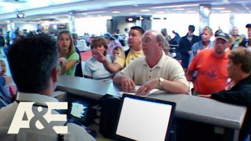 People at airport counter discussing with staff.