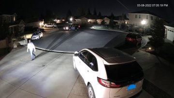 Nighttime cul-de-sac with parked cars and streetlights.