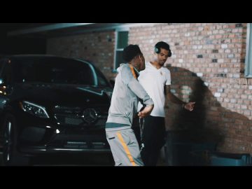 Two people talking by a parked Mercedes-Benz car.