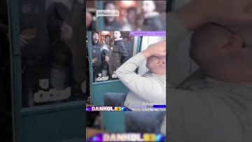 Man reacts while crowd watches through glass window.