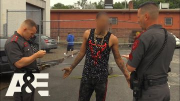 Officers questioning man outdoors next to patrol car.