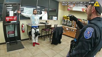 Police confronting man in store with Taser aimed.