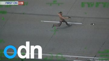 Shirtless man running on road with gun