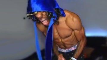 Muscular person wearing a blue hoodie shouting energetically.