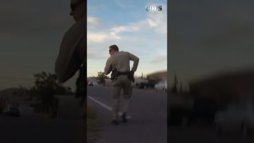 Police officer running on street during sunset.