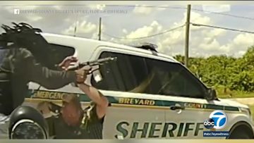 Sheriff deputy drawing gun near patrol car