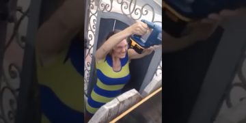 Person using chainsaw near metal gate.