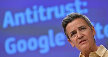 Person speaking in front of antitrust Google backdrop.