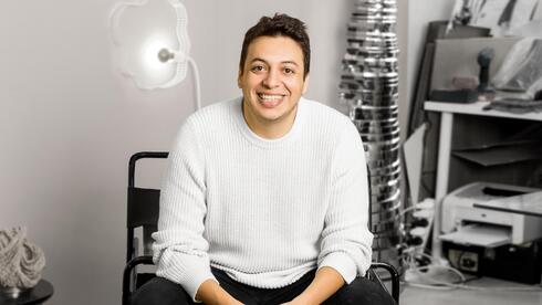 Smiling person sitting in a modern studio setting.
