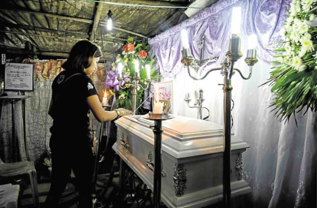 Woman at a funeral wake, lighting candles.