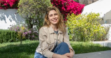 Smiling woman sitting in garden with flowers behind