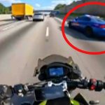 Motorcyclist on highway near a police car.