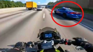 Motorcyclist on highway near a police car.