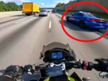 Motorcyclist on highway near a police car.