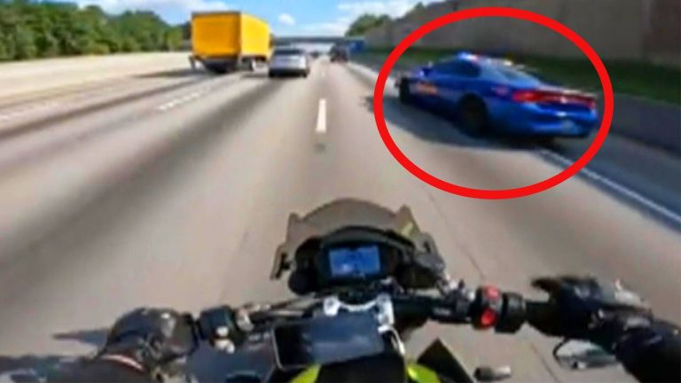 Motorcyclist on highway near a police car.